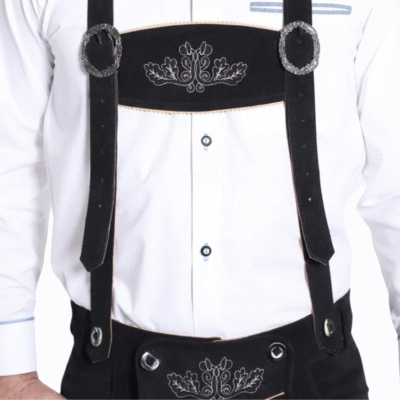 Close-up of black suede suspenders with silver buckles and acorn-oak leaf embroidery, paired with a white dress shirt.