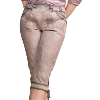 Woman modeling beige traditional knee-length lederhosen with front flap embroidery, side pocket accents, and cuff ties, paired with a lavender blouse.