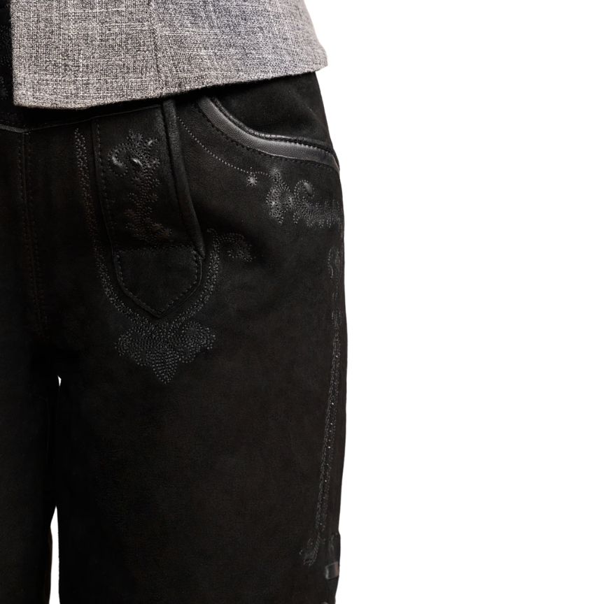Close-up side view of women’s black leather lederhosen shorts featuring intricate tonal embroidery near the pocket and thigh, with smooth leather piping.