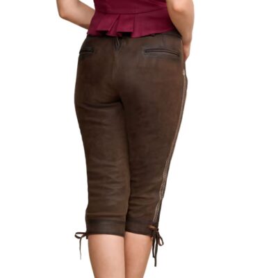 A woman wearing traditional knee-length Lederhosen in dark brown suede, shown from the back. The shorts have a fitted design with a lace-up detail at the back waist and leg hems, and are paired with a red peplum top.