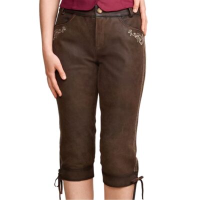 Front view of a woman dressed in dark brown knee-length traditional Lederhosen with subtle beige embroidery on the upper thighs. The shorts feature side seams with decorative stitching and are worn with a maroon top.