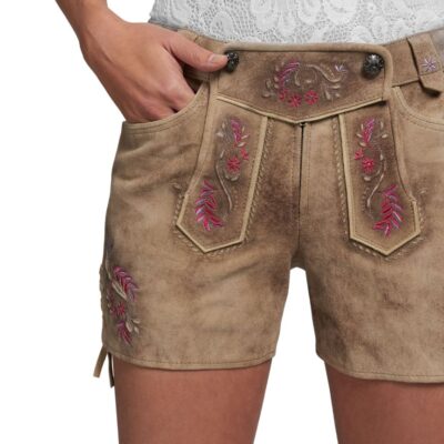 Close-up of women’s beige leather lederhosen shorts with pink and purple floral embroidery on the front flap and leg panels, styled with a white lace blouse.