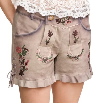 Front view of women’s traditional beige lederhosen shorts with intricate floral embroidery in pink and green, decorative flap detailing, and ruffled hems, styled with a lace blouse.